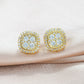 Pair of yellow gold iced out cushion square cluster moissanite stud earrings resting on satin ribbon surface