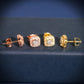 Rose gold and yellow gold iced out cushion square halo solitaire moissanite stud earrings aligned on navy display stand