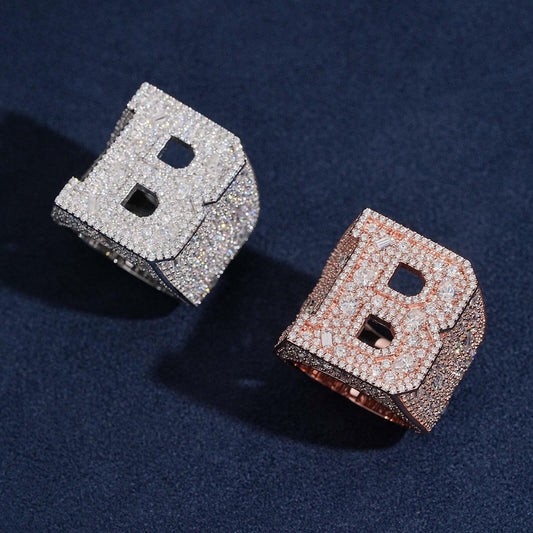 Iced out double letter B moissanite baguette rings in silver and rose gold options on dark blue surface