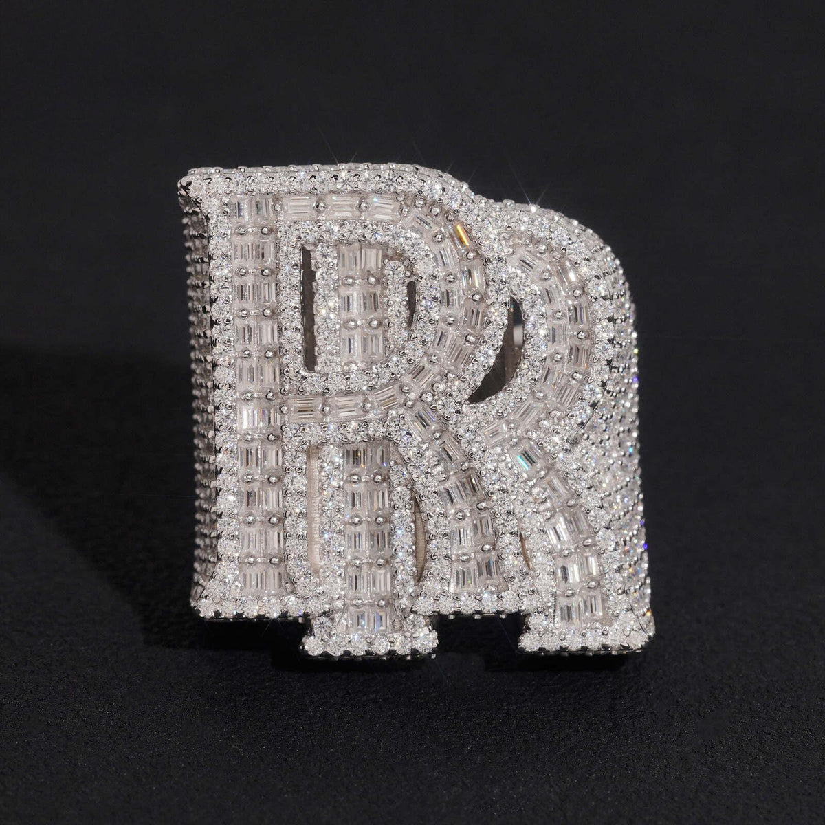 Iced out double letter RR moissanite baguette ring in sterling silver isolated on dark background