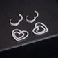 Silver iced out huggie hoop moissanite earrings showing open hinged clasps and removable double heart charms