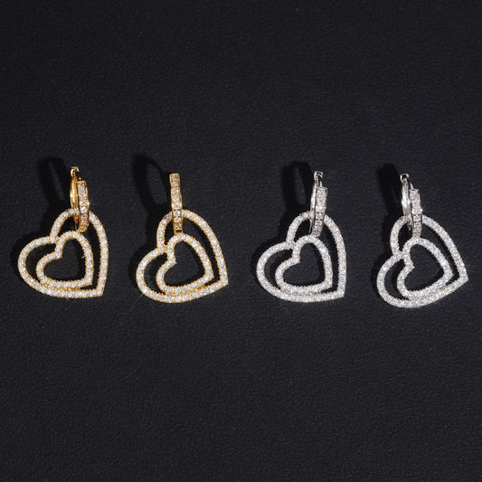 Iced out double open heart dangle huggie hoop moissanite earrings in gold and silver on black background