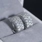 Pair of silver iced out double row pave moissanite huggie hoop earrings presented in velvet jewelry box