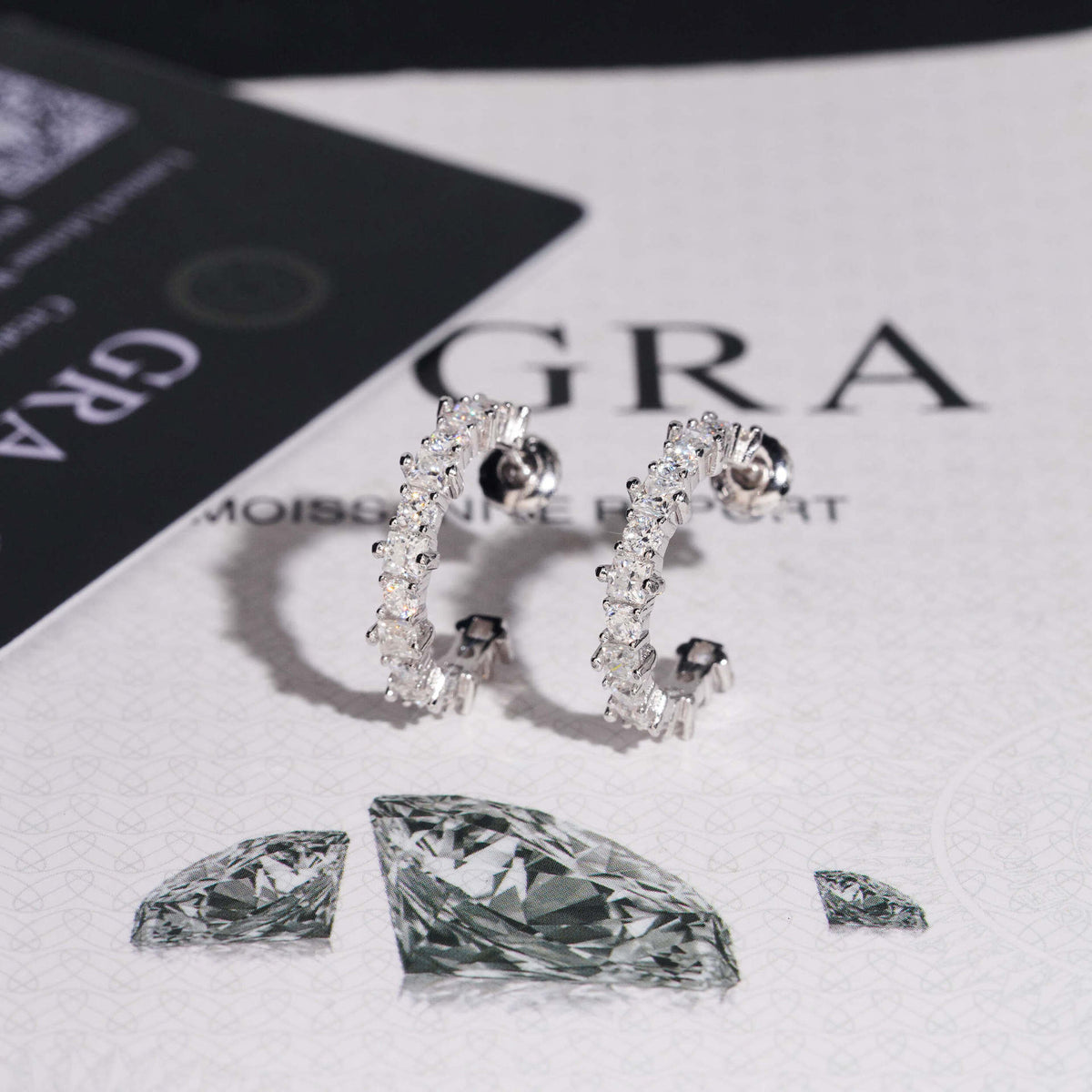 Silver iced out eternity C-shaped half hoop moissanite stud earrings showing posts and screw backs on GRA card