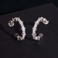 Silver iced out eternity C-shaped half hoop moissanite stud earrings with pave setting on dark background