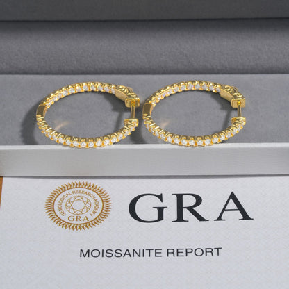 Yellow gold iced out eternity moissanite hoop earrings resting on velvet display box with GRA report card