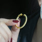 Close-up of hand holding yellow gold iced out eternity moissanite hoop earring near ear