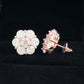 Rose gold iced out flower 7-stone cluster moissanite stud earrings with screw back post on black velvet background