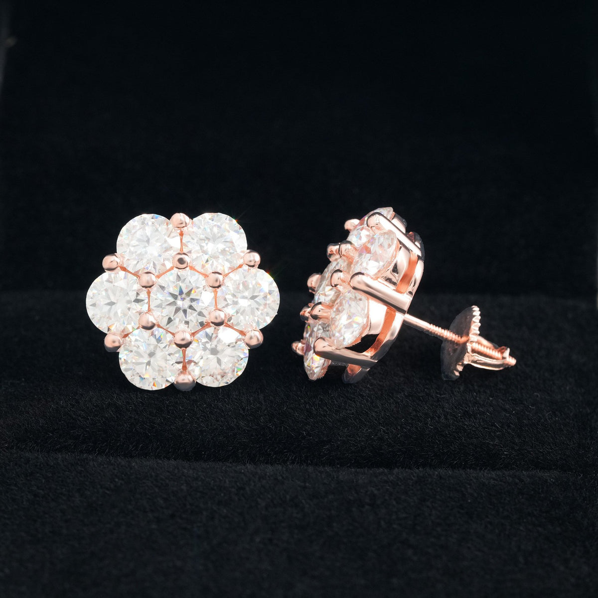 Rose gold iced out flower 7-stone cluster moissanite stud earrings with screw back post on black velvet background