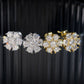 White and yellow gold iced out flower 7-stone cluster moissanite stud earrings aligned on black display stand