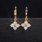 Pair of yellow gold iced out four-leaf clover dangle huggie hoop moissanite earrings showing hinged clasp
