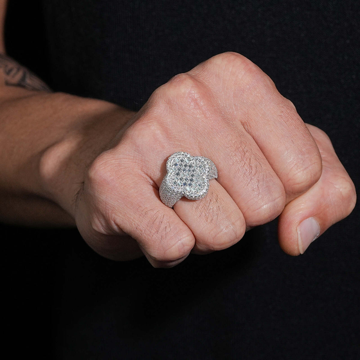Person wearing iced out four-leaf clover moissanite baguette ring on finger