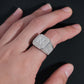 Person wearing iced out four-stone square cluster moissanite ring on finger