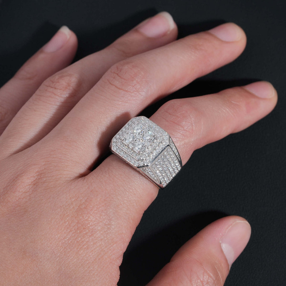 Person wearing iced out four-stone square cluster moissanite ring on finger