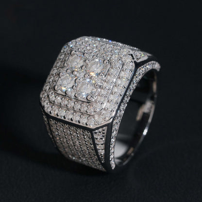 Iced out four-stone square cluster moissanite ring in sterling silver resting on dark background   