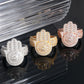 Angled perspective view of iced out hamsa hand moissanite statement rings in silver yellow gold and rose gold