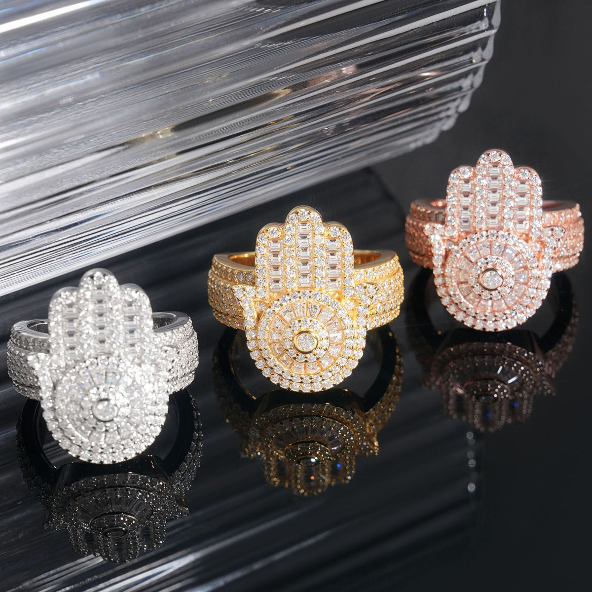Angled perspective view of iced out hamsa hand moissanite statement rings in silver yellow gold and rose gold