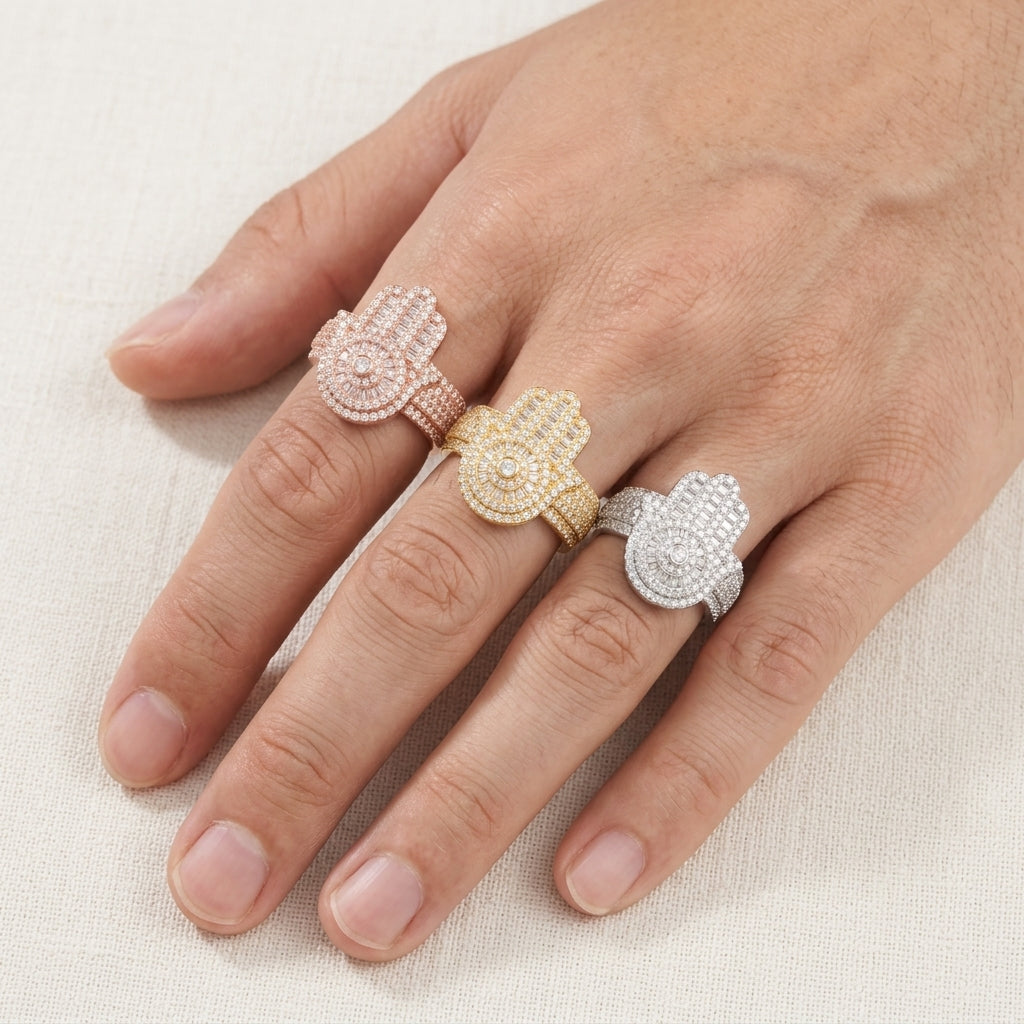 Person wearing three color iced out hamsa hand moissanite baguette statement rings on fingers