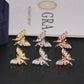 Three-tone iced out marquise butterfly moissanite stud earrings arranged on GRA report card