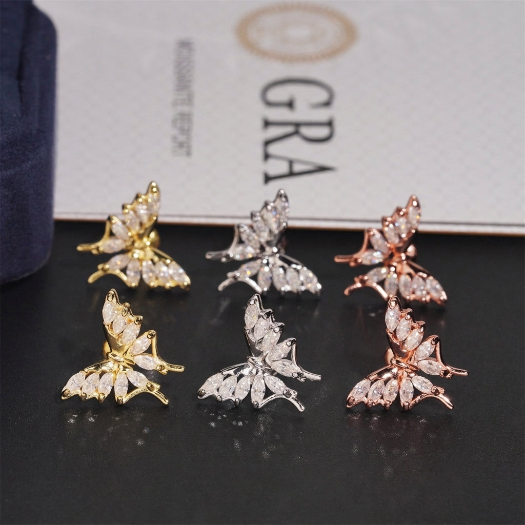 Three-tone iced out marquise butterfly moissanite stud earrings arranged on GRA report card