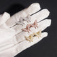 Gloved hand holding silver, rose gold, and yellow gold iced out marquise butterfly moissanite stud earrings for scale   