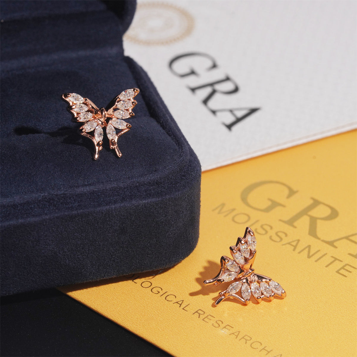Rose gold and yellow gold iced out marquise butterfly moissanite stud earrings displayed with velvet box