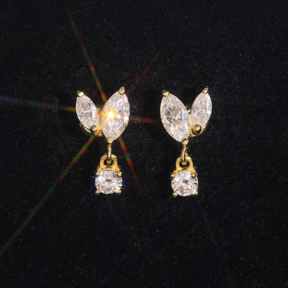 Yellow gold iced out marquise leaf dangle solitaire moissanite stud earrings sparkling on dark background