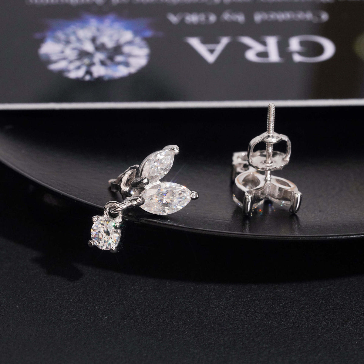 Silver iced out marquise leaf dangle solitaire moissanite stud earrings showing posts and screw backs on GRA card