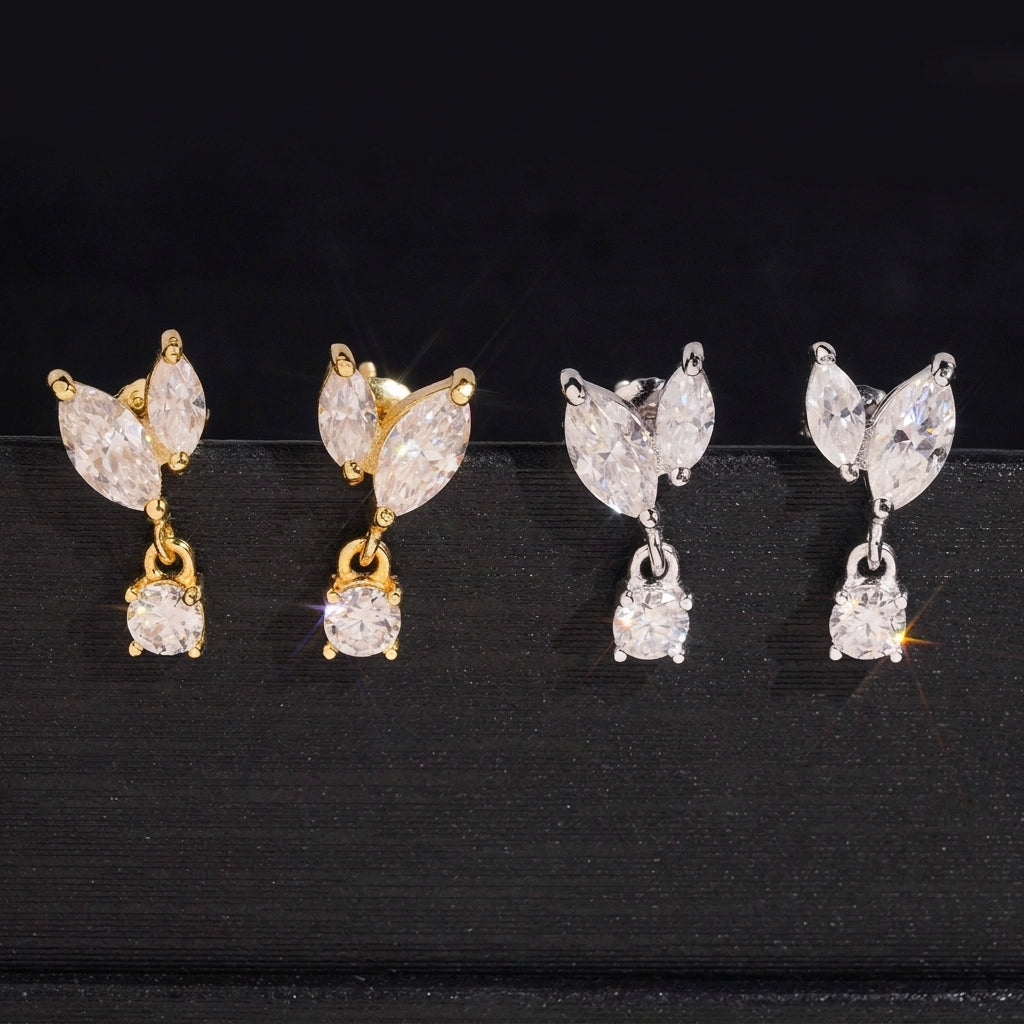 Iced out marquise leaf dangle solitaire moissanite stud earrings in yellow gold and silver on dark surface
