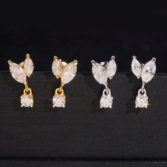 Iced out marquise leaf dangle solitaire moissanite stud earrings in yellow gold and silver on dark surface