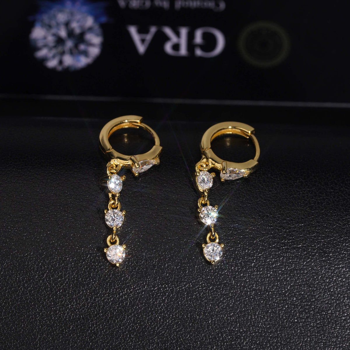 Gold and silver iced out pear cut 3-stone drop dangle huggie hoop moissanite earrings showing hinged clasps