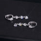 Silver iced out pear cut and 3-stone drop dangle huggie hoop moissanite earrings on dark background