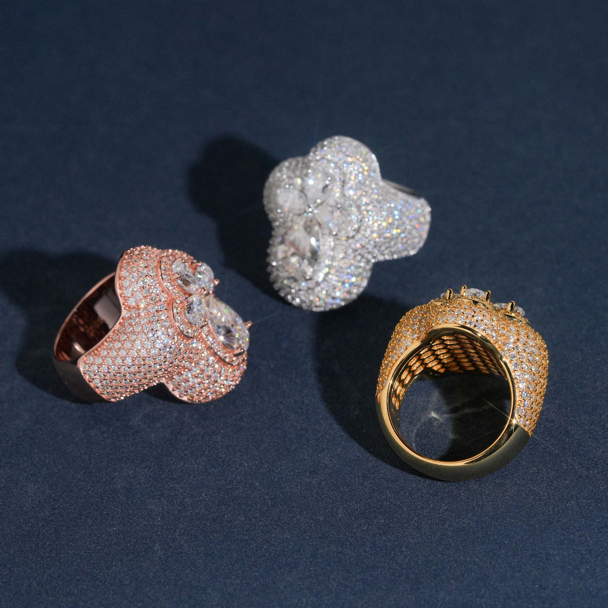 Side angle view of iced out pear cut moissanite clover statement rings showing pave setting details