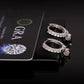 Silver iced out huggie hoop moissanite earrings showing open hinged mechanism and removable pink heart charm