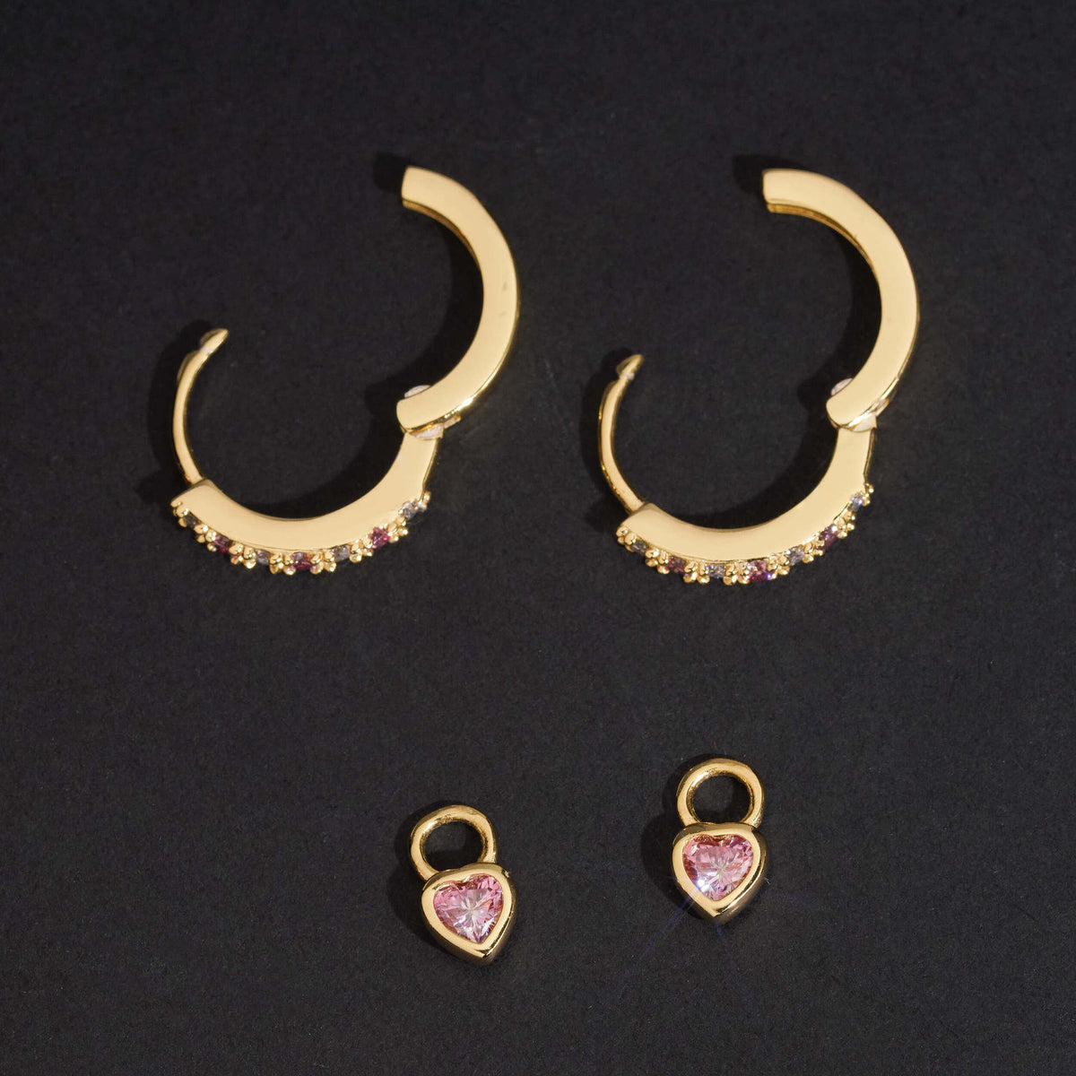 Yellow gold iced out huggie hoop moissanite earrings showing detachable pink heart charms and hinged clasp