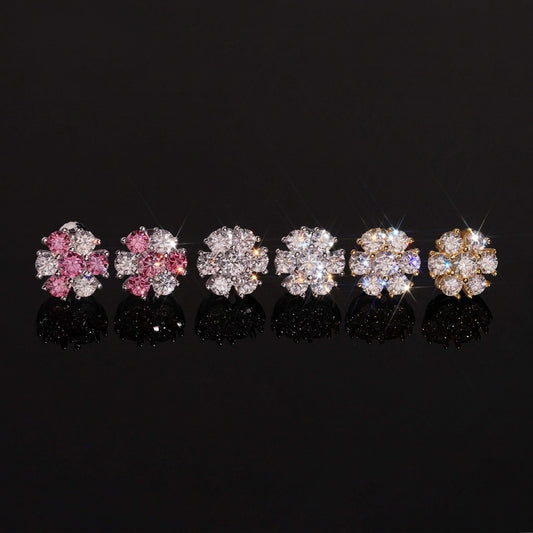 Iced out pink and white flower 7-stone cluster moissanite stud earrings in pink, silver, and gold on dark surface