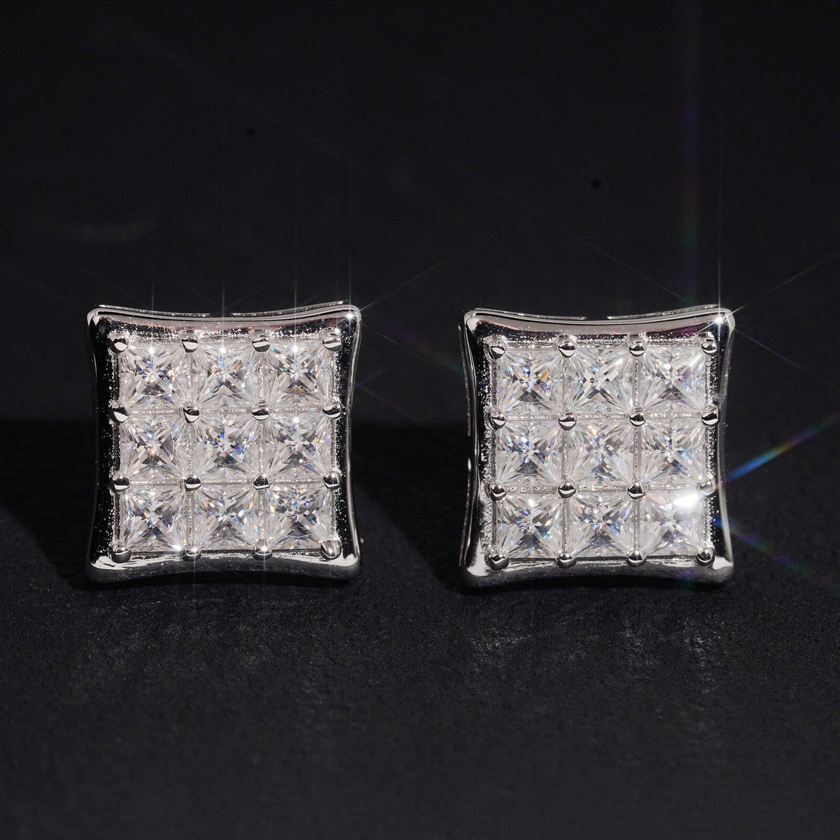Iced out princess cut square cluster moissanite stud earrings sparkling on dark background