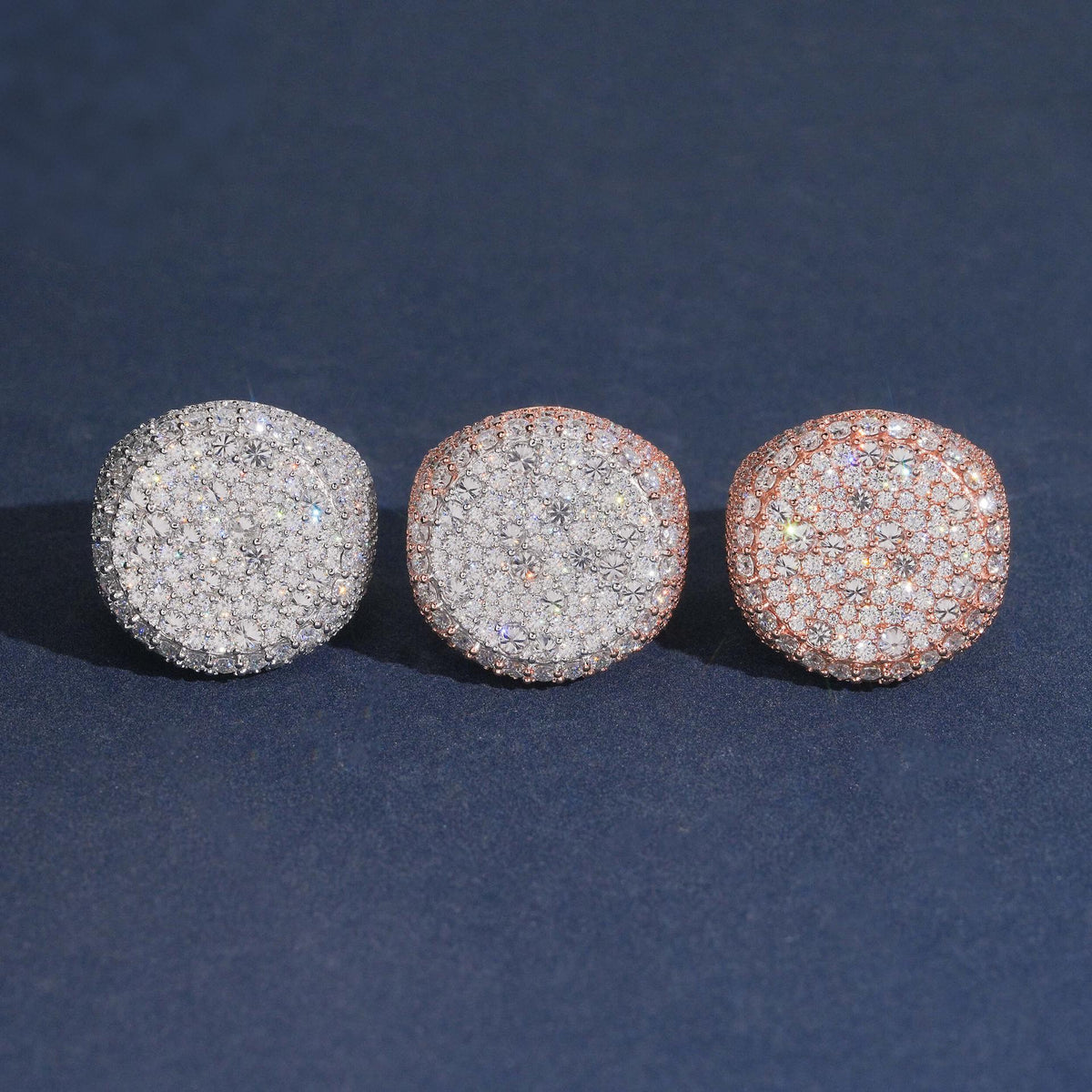 Iced out round flat top moissanite signet rings in silver rose gold and yellow gold on dark blue background
