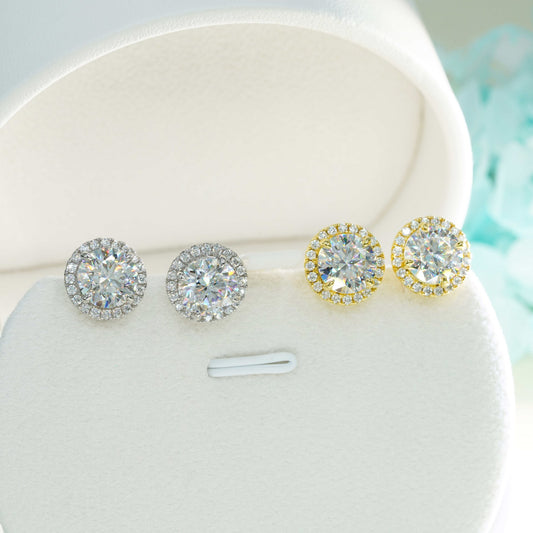 Iced out round solitaire halo moissanite stud earrings in silver and yellow gold in white jewelry box