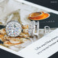 Silver iced out round solitaire halo moissanite stud earrings displayed on magazine background