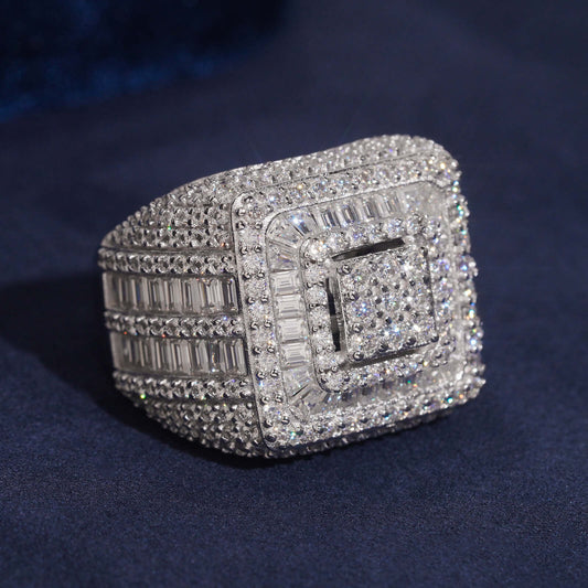 Iced out square tiered halo moissanite baguette ring in sterling silver resting on dark blue surface