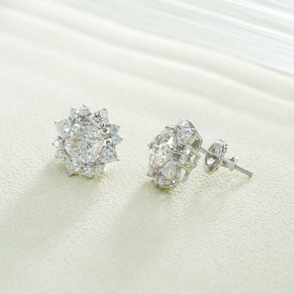 Pair of silver iced out sunburst starburst solitaire moissanite stud earrings on white textured surface