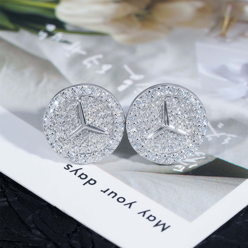 Silver iced out three-point star emblem moissanite stud earrings resting on white floral card