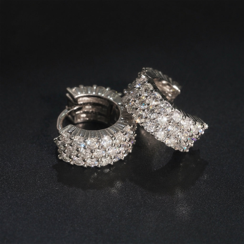 Pair of silver iced out triple row moissanite huggie hoop earrings showing hinged clasp mechanism