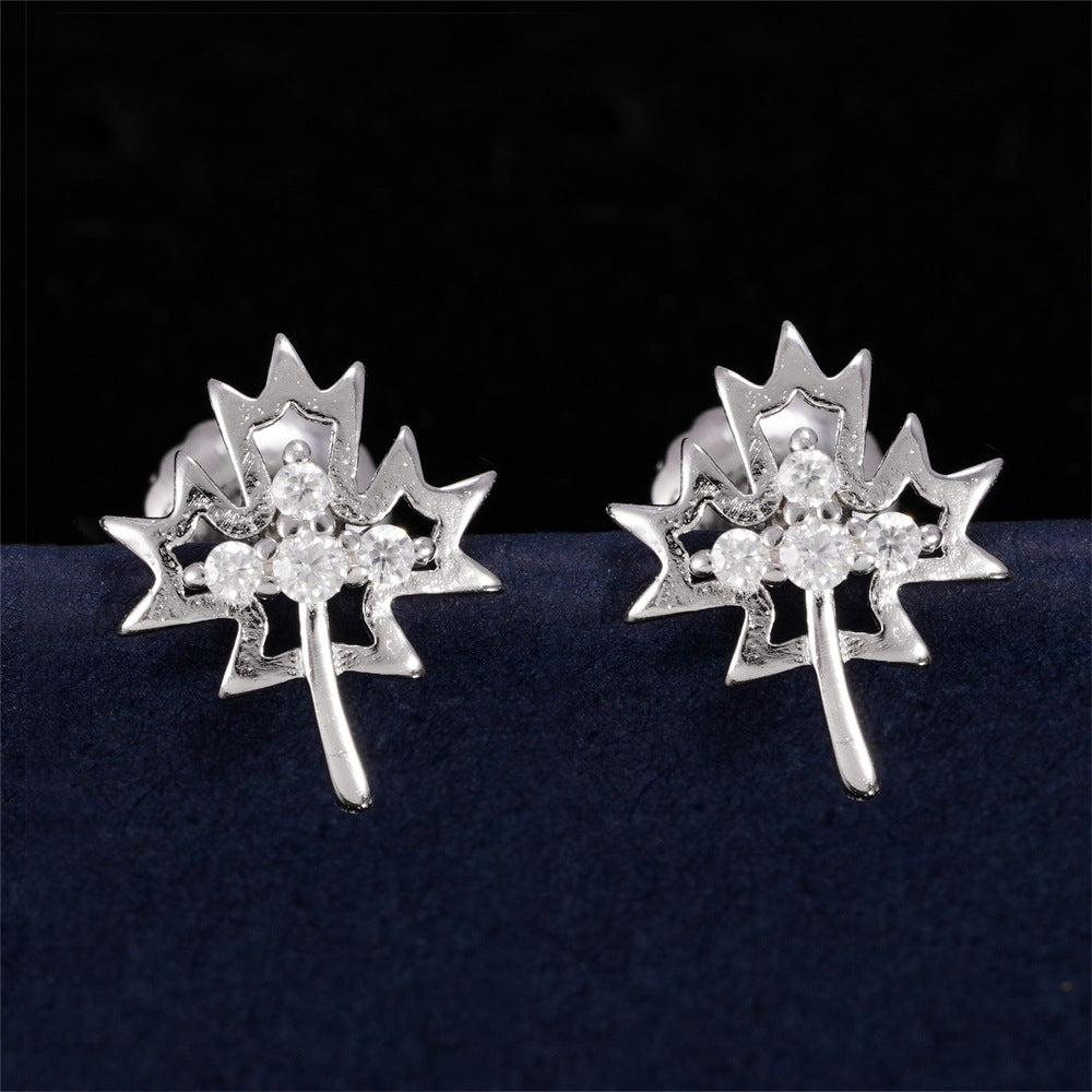 Silver iced out weed leaf maple leaf moissanite stud earrings aligned on dark background