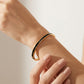 Tory Burch Icon Thin Enamel Bracelet with Double T design, featuring gold-tone and black enamel accents, from Zerra Jewelry.