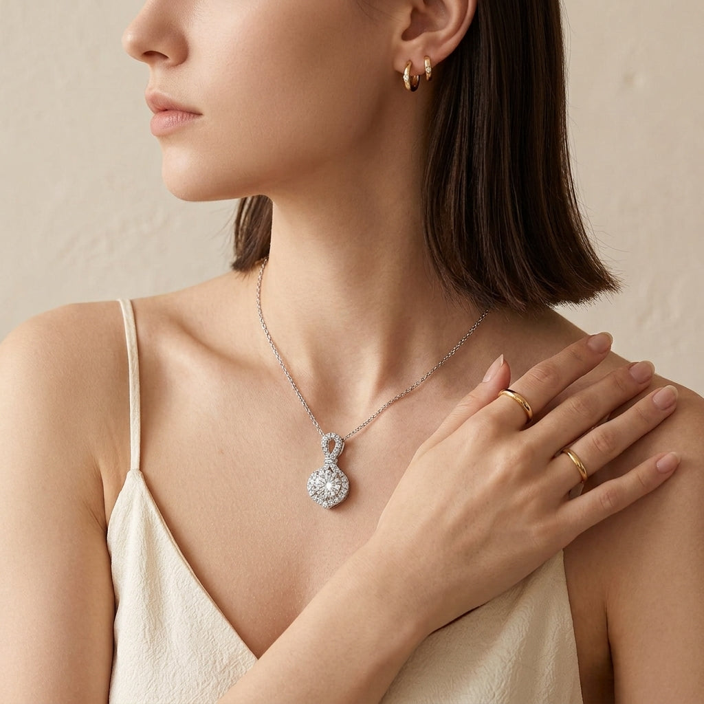 Model wearing infinity knot round diamond halo pendant necklace with white top.