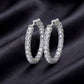 Pair of inside-out round cut lab grown diamond hoop earrings resting on dark black silk