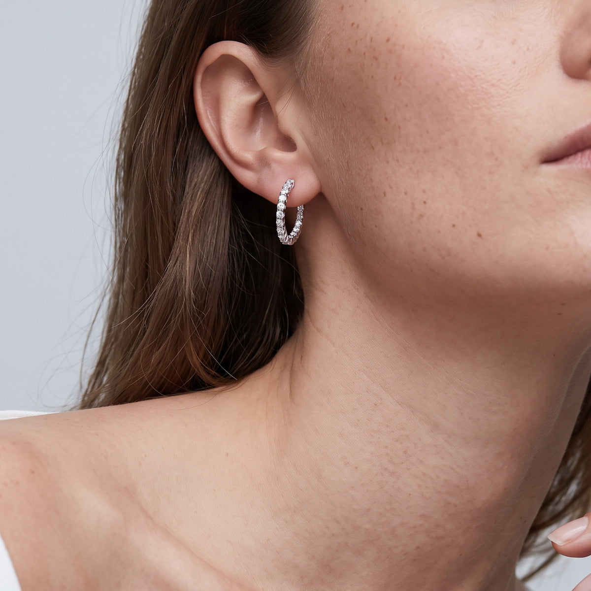 Model wearing inside-out round cut lab grown diamond hoop earring on earlobe