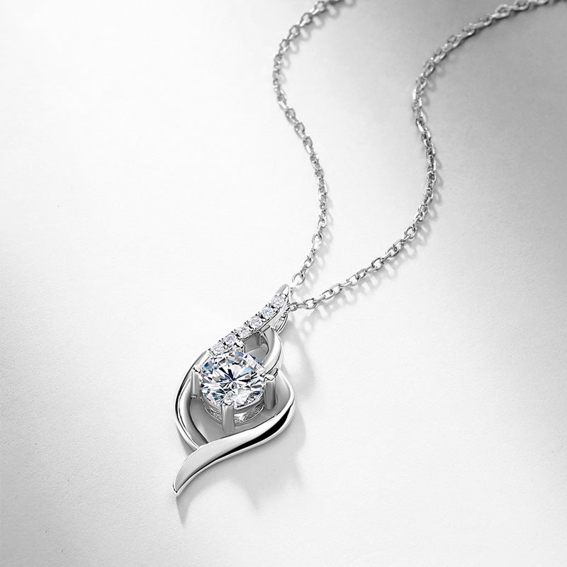 Angled layflat view of round diamond intertwined swirl pendant necklace on white background.